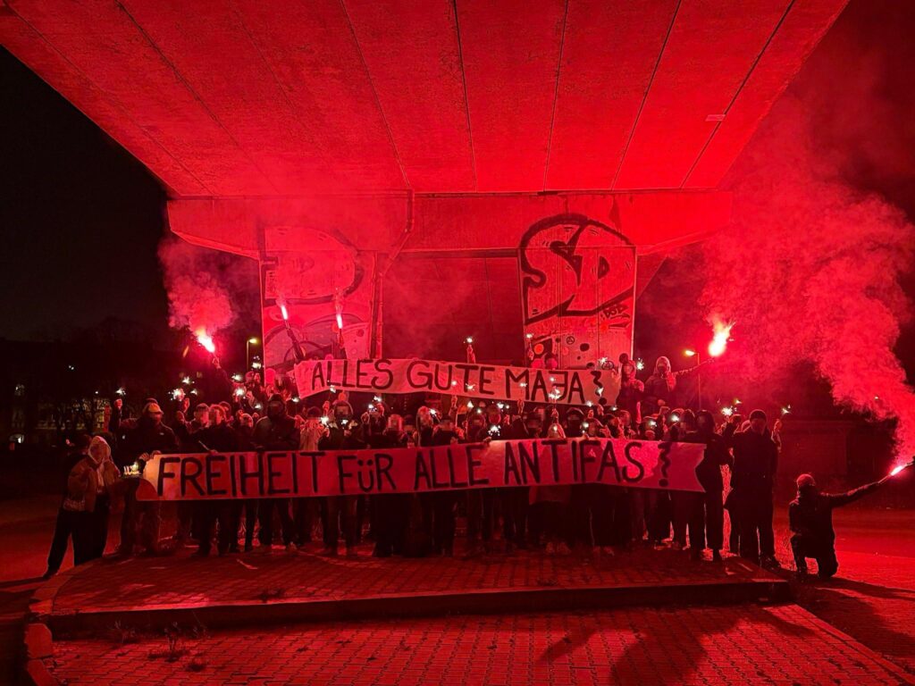 Solifoto mit Pyro, Wunderkerzen und Banner "Alles Gute Maja! Freiheit für alle Antifas!"